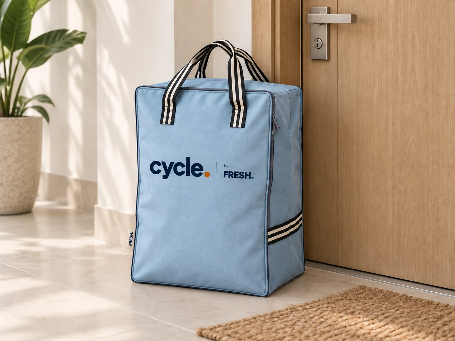 A blue Cycle laundry bag resting beside a residential front door, ready for pickup